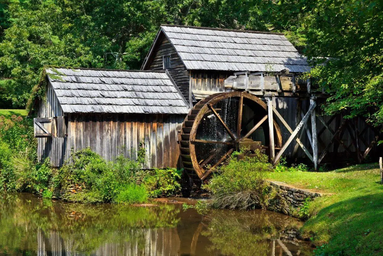 A water mill with two wooden houses next to it.