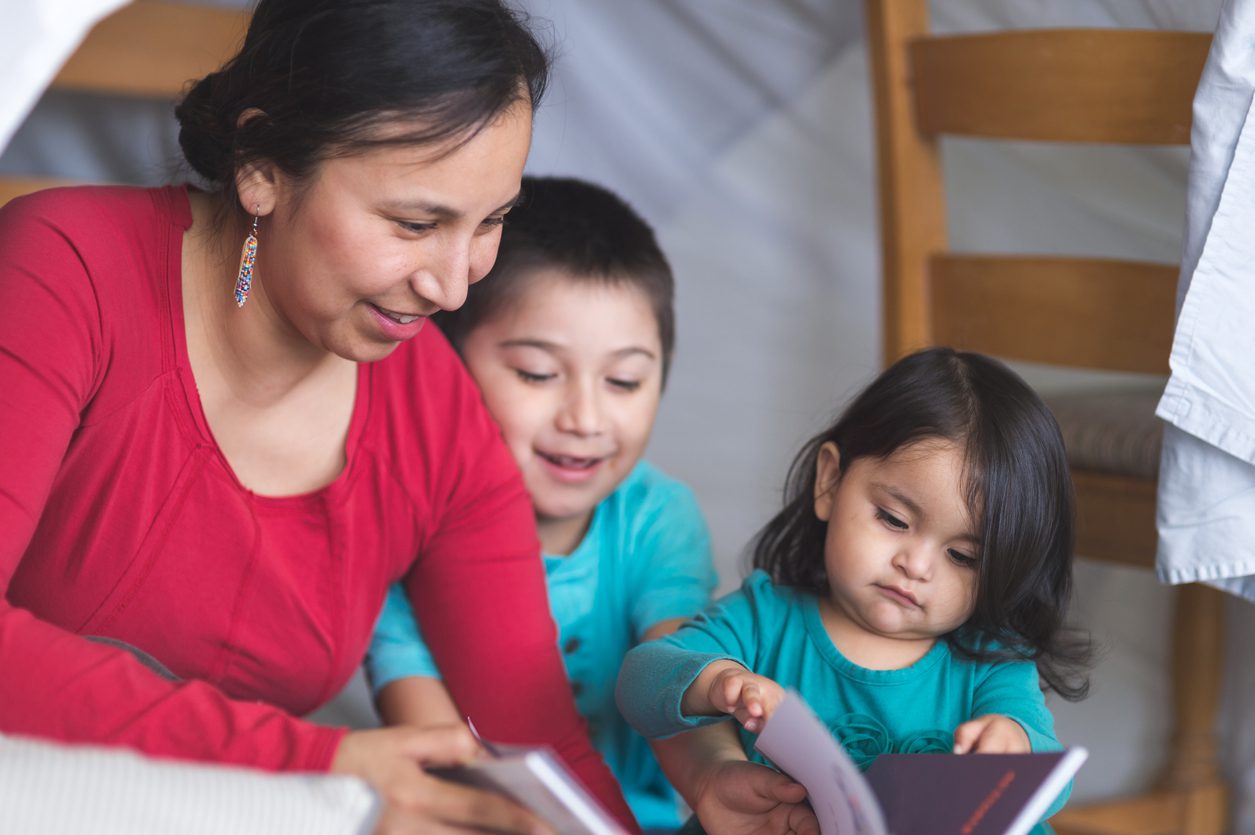 A woman and two children reading books.