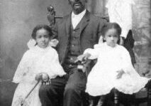 A man sitting in front of two children.