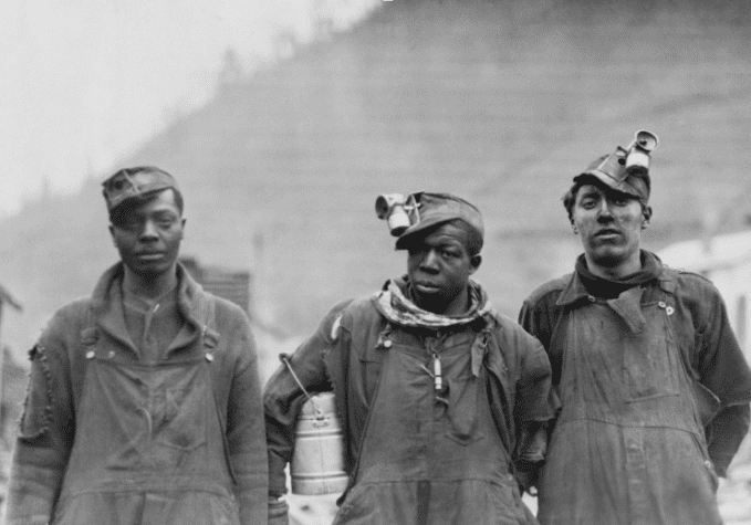 Three Black miners wearing work clothes.