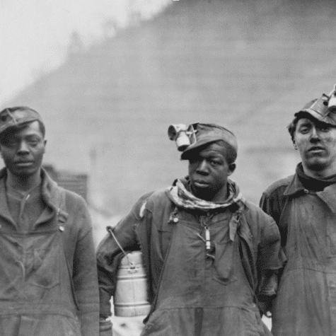 Three Black miners wearing work clothes.