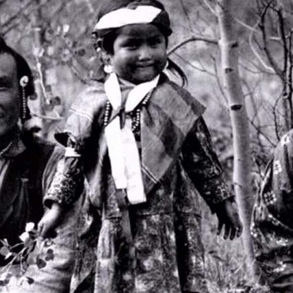 A young girl in native dress with two men.