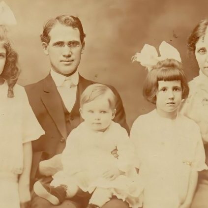 A family photo of an old man and three young girls.